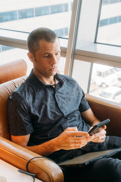 Man in Airport Lounge Texting on Phone