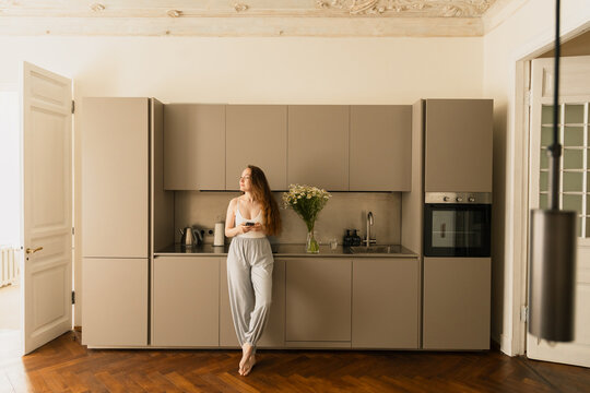  Woman in Homewear Standing in Modern Kitchen with Phone