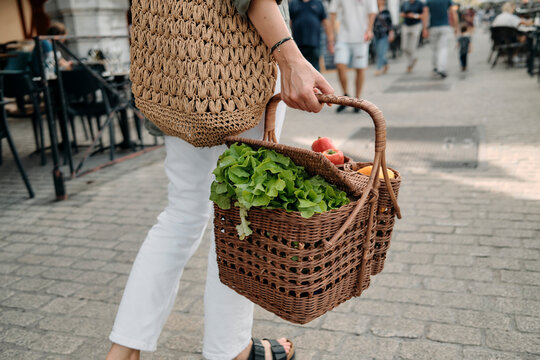 Woman Carrying Wicker Basket Full Of Fresh Greens And Fruits At Outdoo