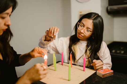 women lighting colorful candles celebrating tradition at home