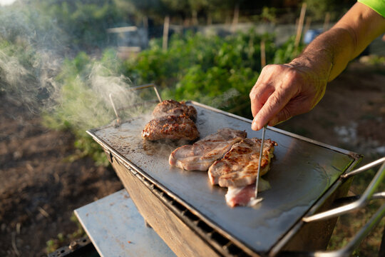 Man grilling pork and burgers on barbecue