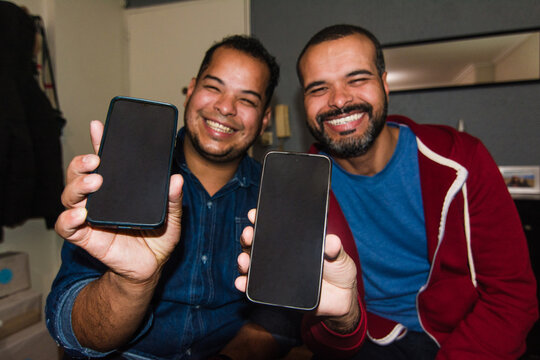 Two friends showing blank phone screens and smiling 