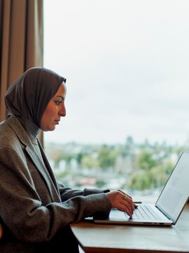 Professional Woman Working on Laptop With City View Nearby