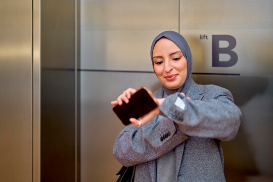 Woman Checking Her Smart Watch While Waiting by the Elevator