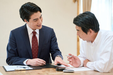 士業のサポートで書類を記入するシニア男性