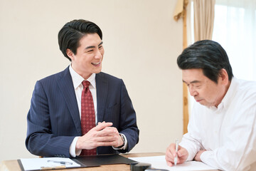 Obraz premium 士業のサポートで書類を記入するシニア男性