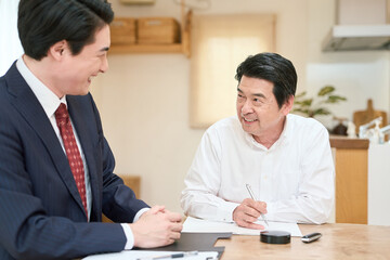 Obraz premium 士業のサポートで書類を記入するシニア男性