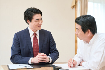 士業のサポートで書類を記入するシニア男性