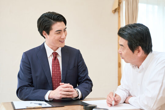 士業のサポートで書類を記入するシニア男性