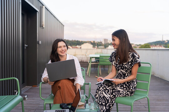Two Women Collaborating on a Rooftop During Sunset