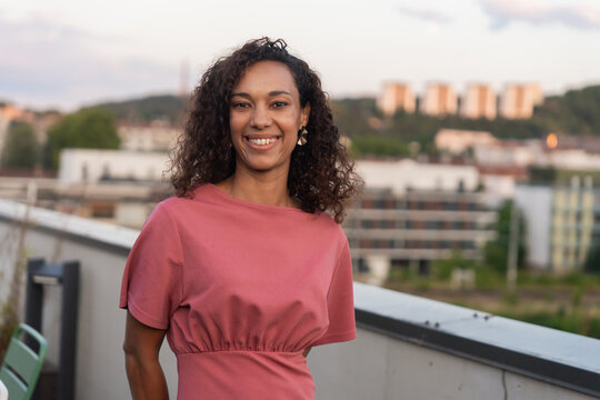 Woman Smiling on a Rooftop With City Skyline in the Background