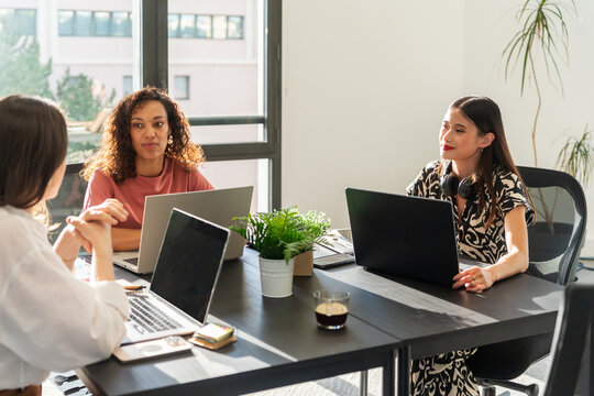 Three Women Discussing Ideas in a Modern Office Setting