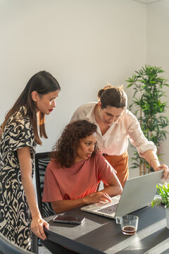 Women Collaborating on a Laptop in a Bright Office Space