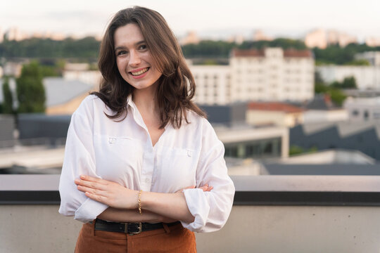 Smiling Woman Poses on Rooftop Terrace in City During Sunset
