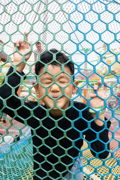 Boy playing behind a safety net at playground