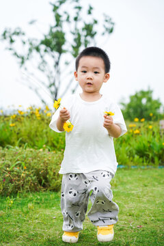 Little boy holding yellow flowers in the park