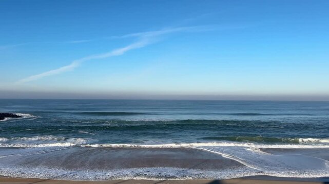 Waves and backwash from the sea on a beautiful blue sky day on a sandy beach.