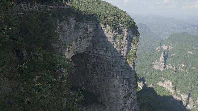 A breathtaking view of the limestone cliffs and natural archway at Tianmen Mountain in Zhangjiajie, China. Ideal for travel documentaries and nature exploration content.