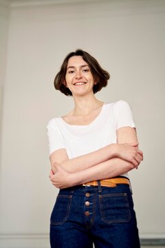 Smiling Woman in Stylish Outfit Stands Confidently Indoors
