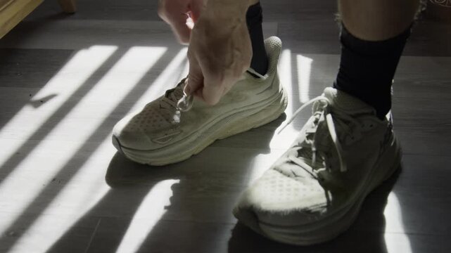 Tying running shoes inside. Man, male tying his shoelaces at home before going out