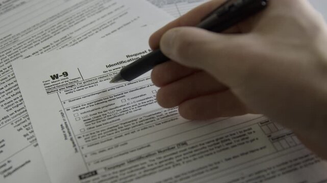 Person filling out a W-9 form. Request for Taxpayer Identification Number and Certification. Person filling out tax form from IRS.