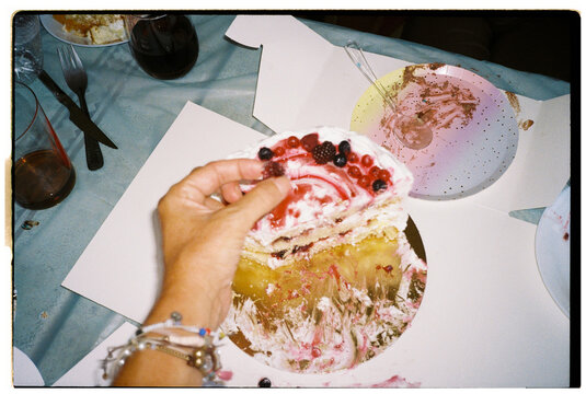 Hand holding slice of berry birthday cake