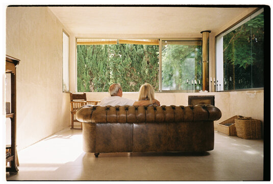 Elderly couple sitting on leather sofa at home