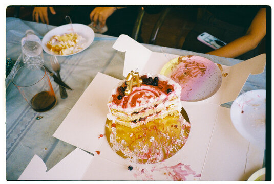Half-eaten birthday cake on messy table