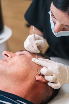 Man receiving professional facial skin treatment at beauty clinic