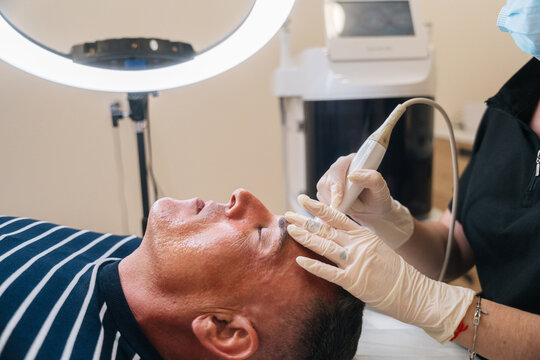 Man receiving professional facial skincare treatment at clinic