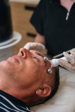 Man receiving microcurrent facial treatment for anti-aging