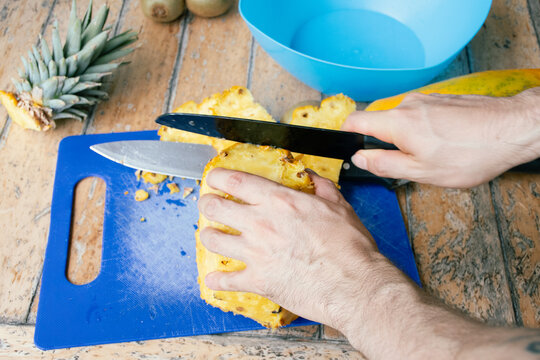 Cutting Fresh Pineapple on a Blue Cutting Board in a Kitchen