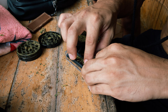 Hands Rolling a joint on a Wooden Table