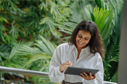 Business Woman Using Tablet on a Balcony Surrounded by Greenery