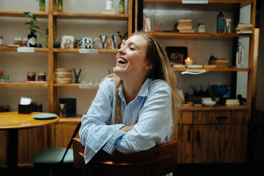 Woman Laughing in a Cozy Cafe Surrounded by Handmade Crafts