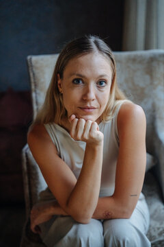 Woman Sitting in a Chair With Thoughtful Expression Indoors