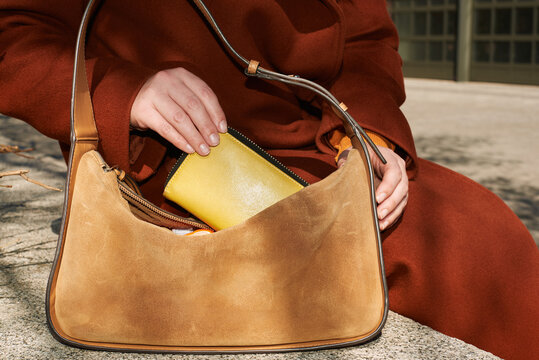 A woman takes a wallet out of her bag