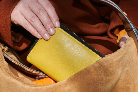 Person storing a yellow wallet in a handbag