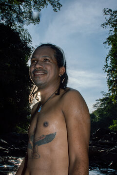 Man Standing by a Stream With Tattoos Under a Clear Sky