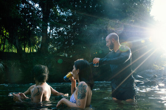 Friends Enjoying Drinks While Swimming in a River During Sunset