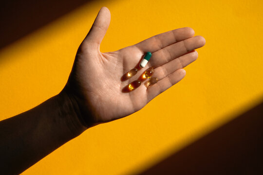 Hand holding pills in sunlight. Studio shot with copy space