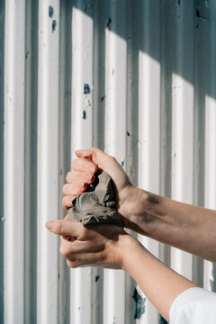 Hands Molding Gray Clay Against a Striped Background
