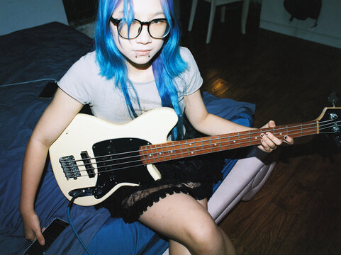 A blue haired female bass guitarist