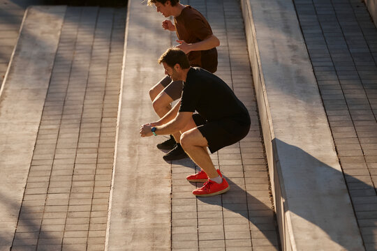 Outdoor squat training on stairs with personal trainer