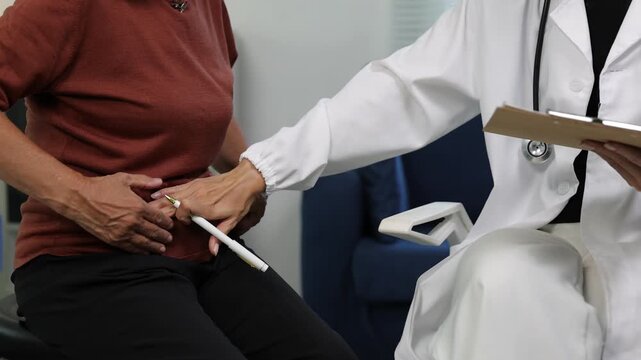Doctor examining an elderly patient's abdomen. Professional female physician consulting an older woman with abdominal pain, palpating the stomach during a medical examination in a clinic.