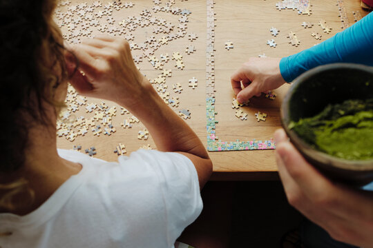 Closeup of two people working together to solve a puzzle