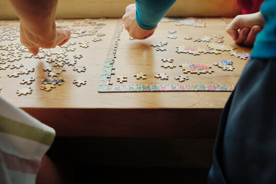 Closeup of hands working together to solve a puzzle