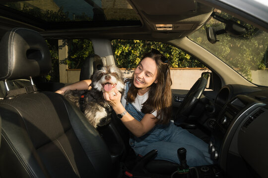Smiling woman enjoying time with her dog inside a car before a trip