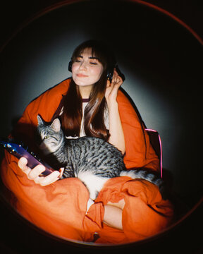  Cozy Moment: Woman with Cat in Orange Blanket Listen To Music