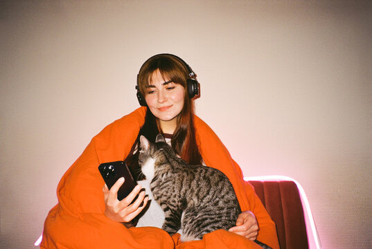 Cozy Moment: Woman with Cat in Orange Blanket Listen To Music